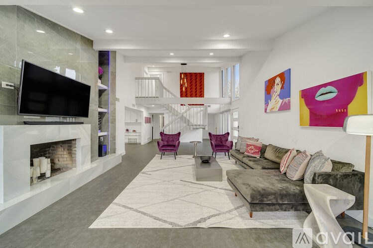 A modern living room with a grey sofa, a fireplace, and a television.