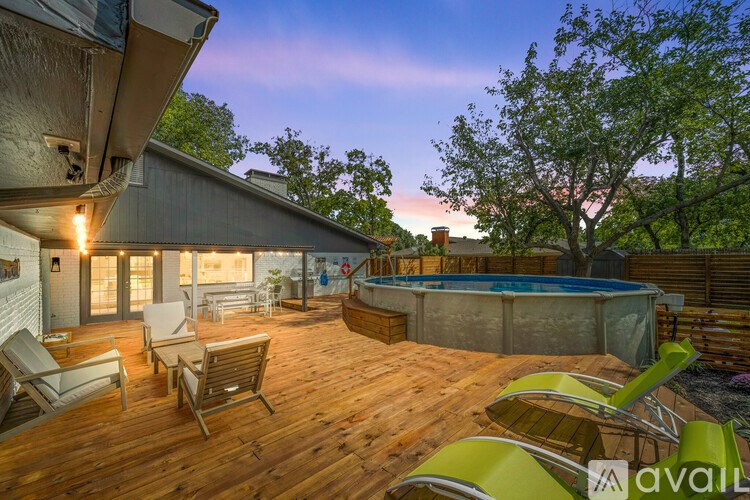 A wooden deck with chairs and a hot tub is surrounded by trees.