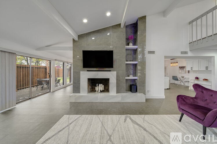 A modern living room with a purple chair and a fireplace.