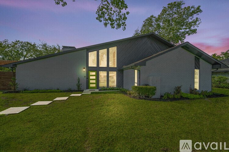 A modern house with a large front yard and a clear sky above.