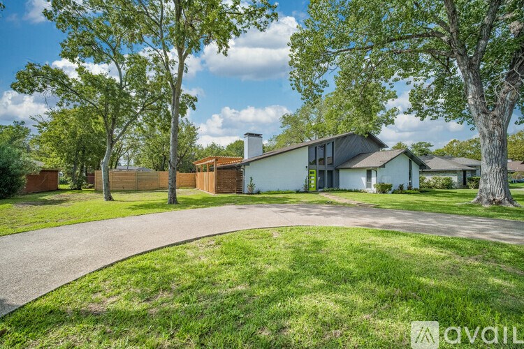 A house with a driveway and trees in front of it.