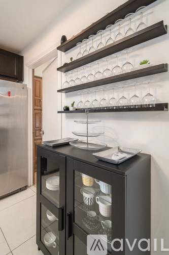 A black cabinet with glass doors and shelves above it.