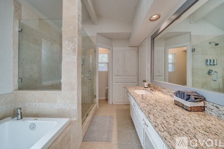 A bathroom with a tub, sink, and mirror.
