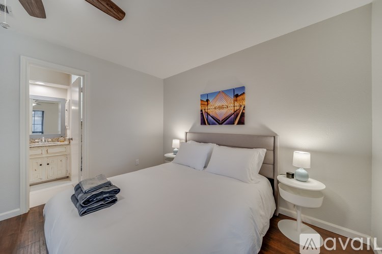 A bedroom with a large bed, a white nightstand, and a painting on the wall.