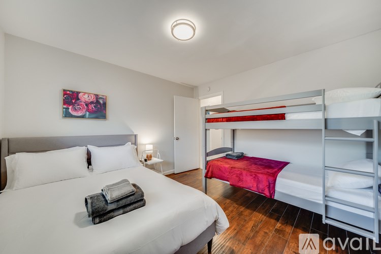 A bedroom with a white bed and a red bed in the background.