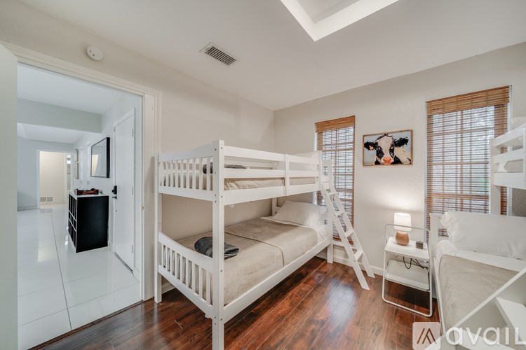 A room with white bunk beds and a wooden floor.