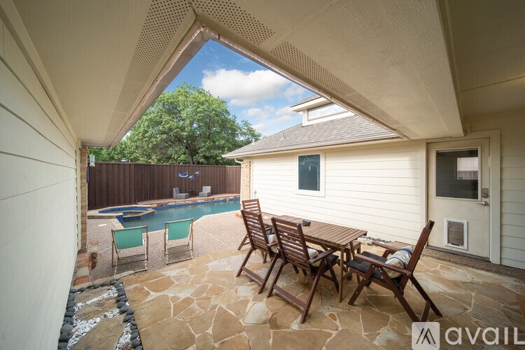 A patio with a table and chairs overlooking a pool.