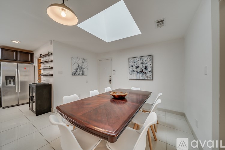 A modern kitchen with a wooden table and white chairs.