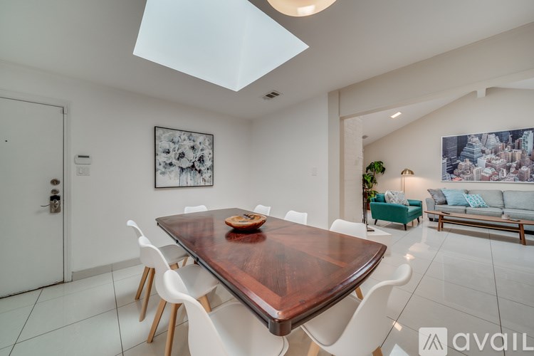 A modern dining room with a wooden table and white chairs.