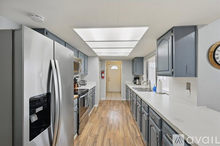 A modern kitchen with a refrigerator on the left and cabinets on the right.