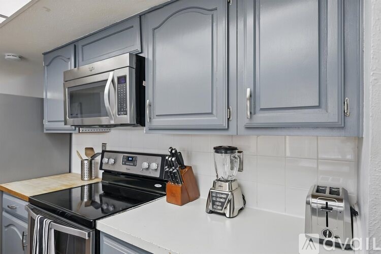 A kitchen with a black stove top oven and a silver microwave above it.