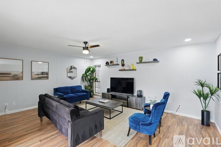 A living room with a blue chair and a black couch.