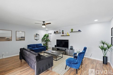 A living room with a blue chair and a black couch.
