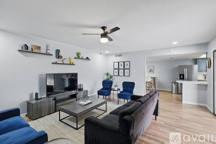 A living room with a black couch, a television, and a ceiling fan.