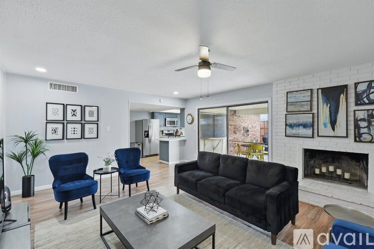 A living room with a black couch, blue chairs, and a fireplace.