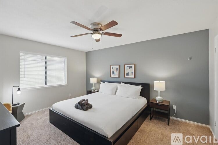 A bedroom with a large bed, a ceiling fan, and two lamps.