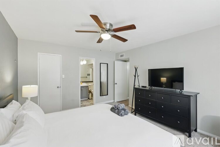 A bedroom with a bed, dresser, and television.