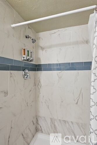 A bathroom with a white tub and a shower head.