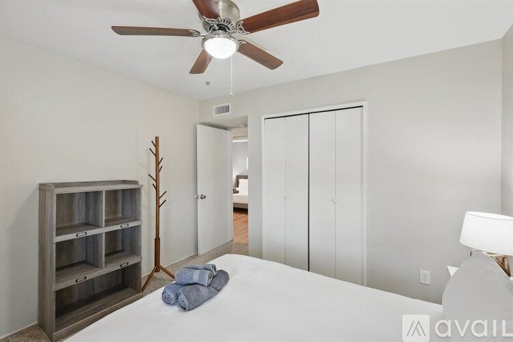 A bedroom with a bed, a ceiling fan, and a cabinet.