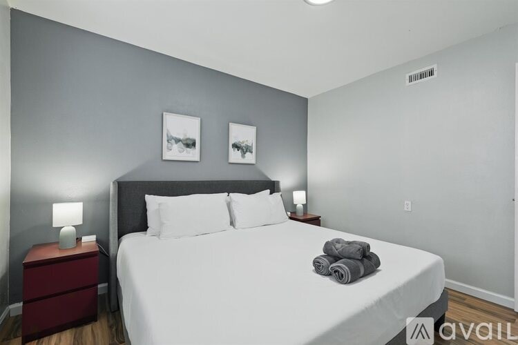 A bedroom with a large bed and two pictures on the wall.