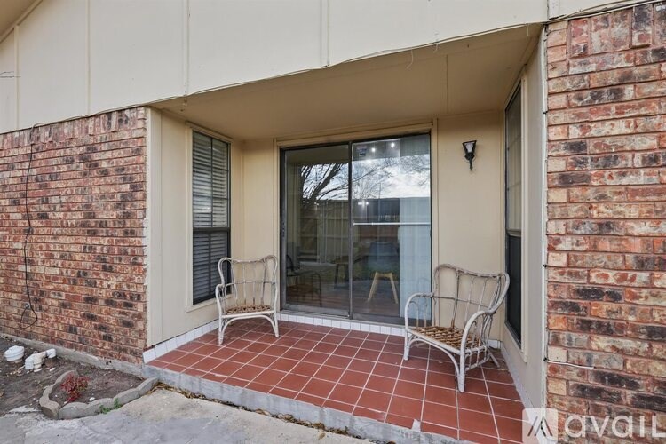 A patio with a chair and a table is outside a brick building.