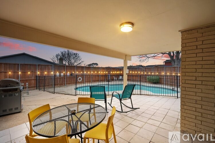 A patio with a table and chairs overlooking a pool.