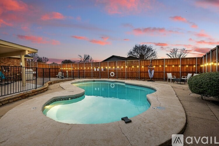 A swimming pool surrounded by a fence and lights.