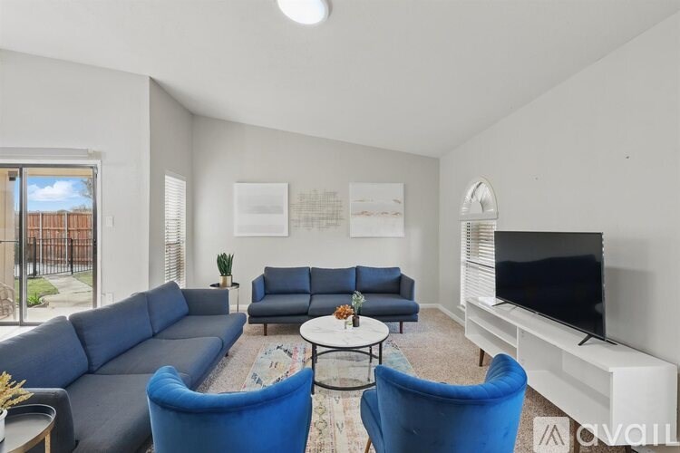 A living room with a grey sofa, blue armchairs, and a television.