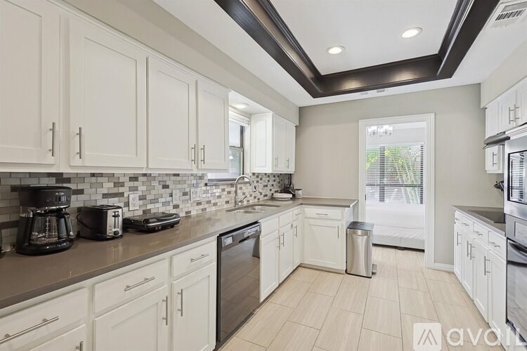 A kitchen with white cabinets and a black counter top.