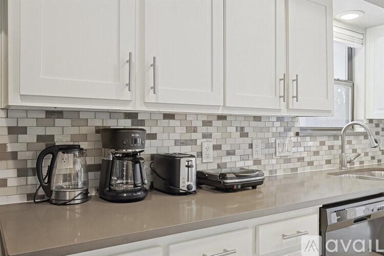 A kitchen counter with a toaster, coffee maker, and kettle on it.