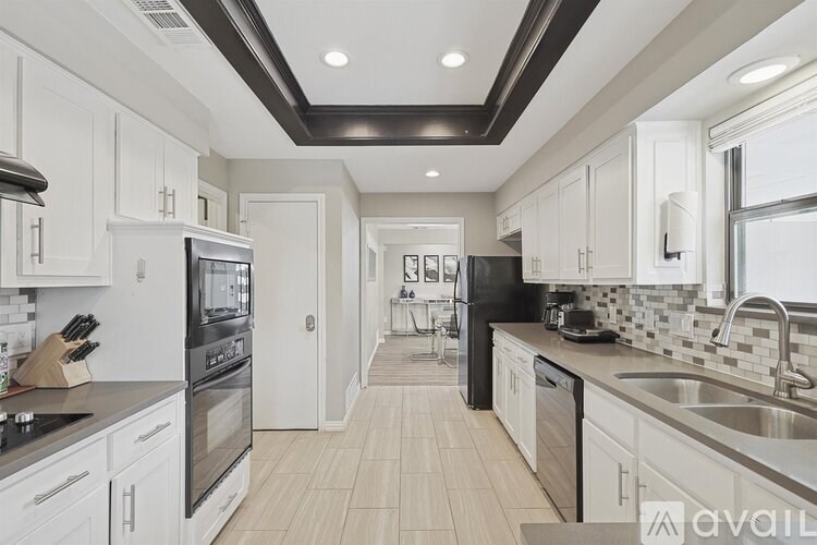 A modern kitchen with white cabinets and a black countertop.