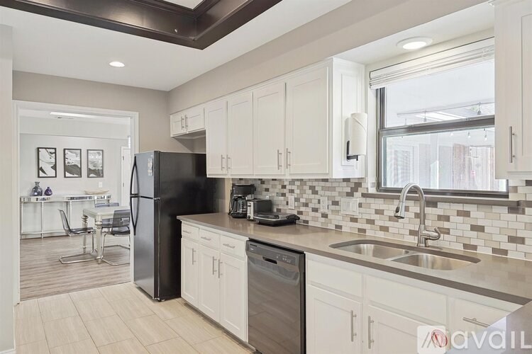 A kitchen with white cabinets and a black refrigerator.