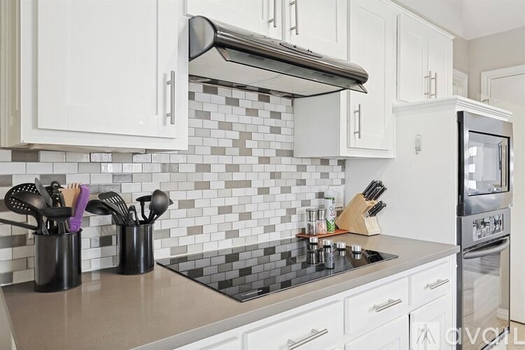 A kitchen with white cabinets and a black and white checkered backsplash.