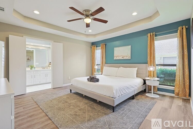 A bedroom with a large bed and a ceiling fan.