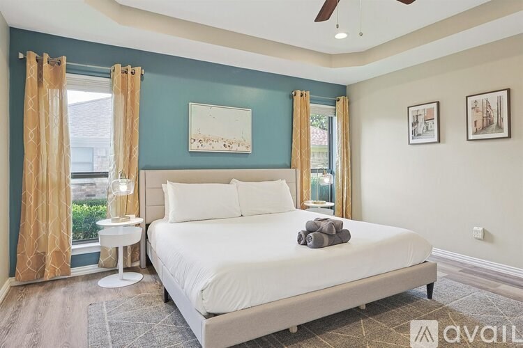 A bedroom with a bed, a window with curtains, and a ceiling fan.