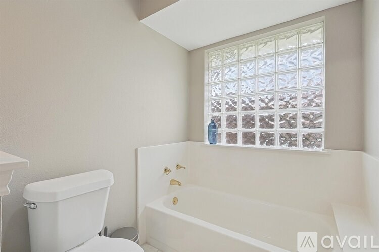 A white bathtub with a window above it.