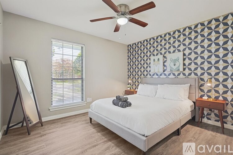 A bedroom with a bed, a ceiling fan, and a wall with a geometric pattern.