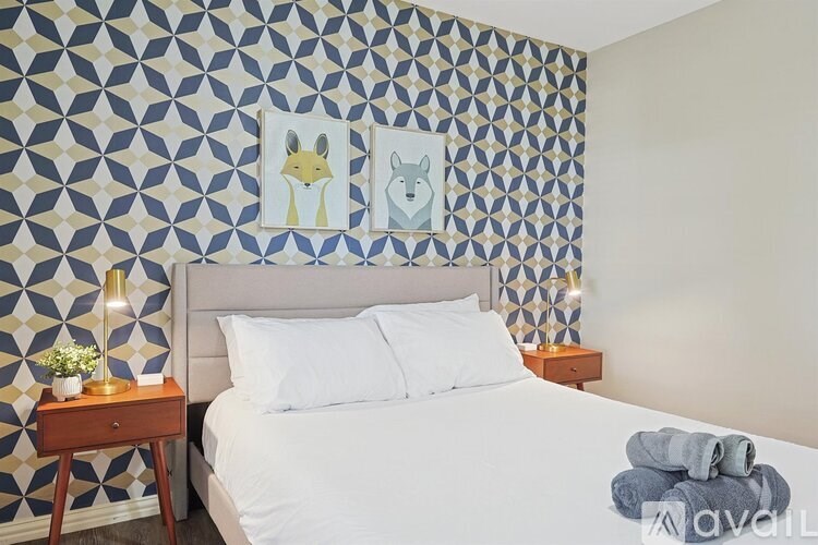 A bedroom with a patterned wallpaper and a bed with white pillows.