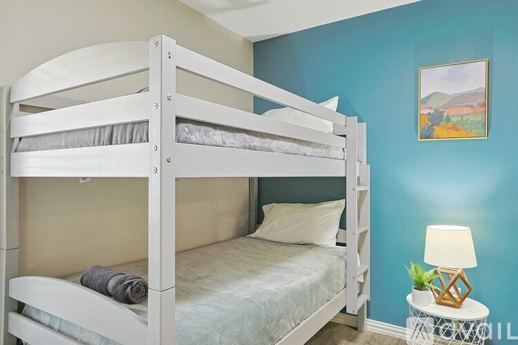 A white bunk bed with a white pillow and a white blanket.