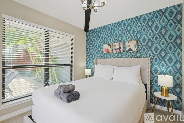 A bedroom with a white bed and a chandelier.