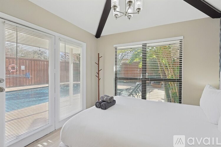 A bedroom with a large bed and a view of a pool through the window.