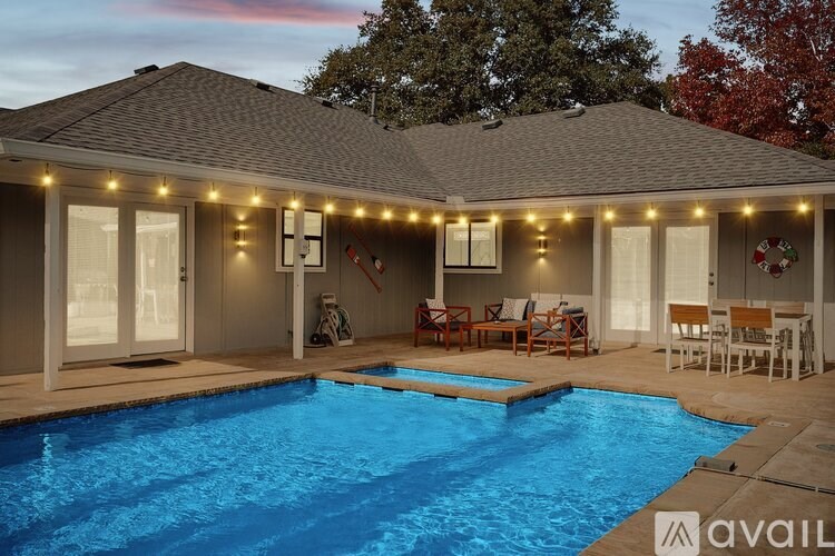 A house with a pool and lights on the porch.