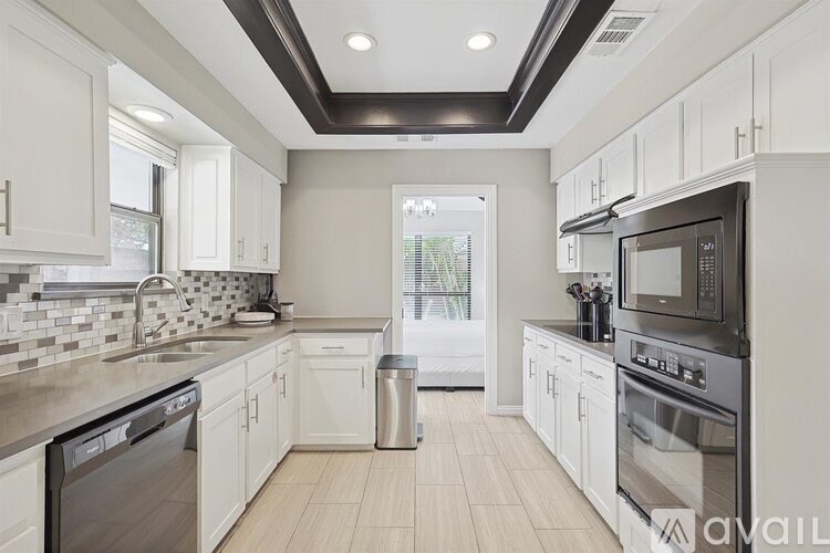 A modern kitchen with white cabinets and stainless steel appliances.