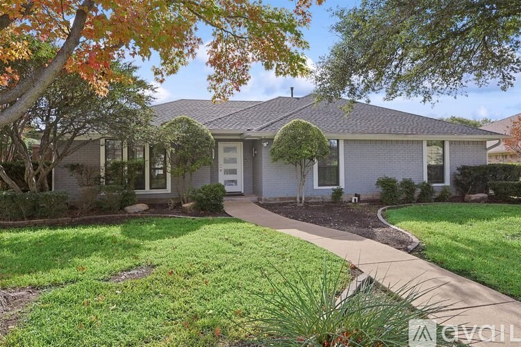 A house with a white front yard and a tree with orange leaves.