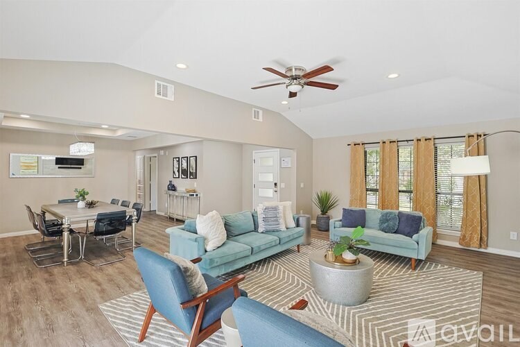 A living room with a blue sofa and a dining table with chairs.