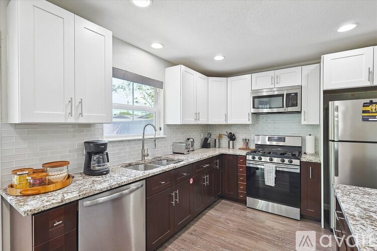 A kitchen with white cabinets and a stainless steel refrigerator.