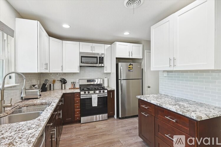 A kitchen with white cabinets and a marble countertop.