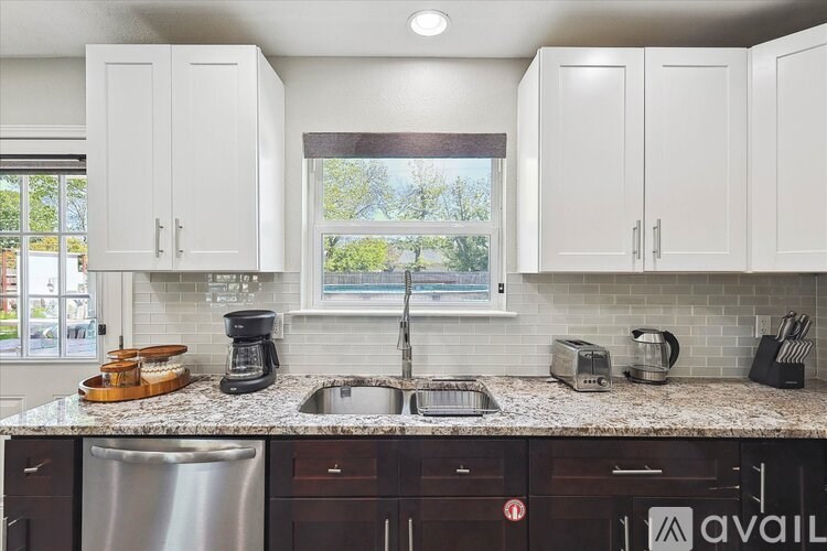 A kitchen with white cabinets and a granite countertop.
