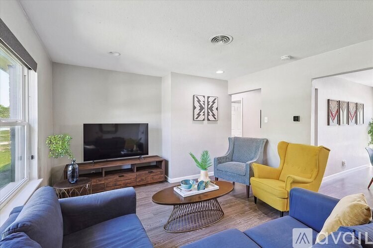 A living room with a grey couch, a yellow chair, a brown coffee table, and a flat screen TV.