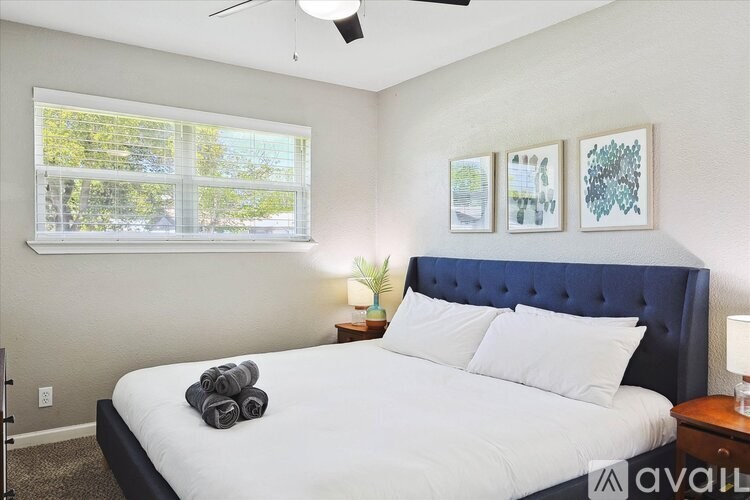 A bedroom with a bed, two lamps, and three pictures on the wall.